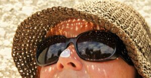 mujer con sombrero lentes de sol y protector solar